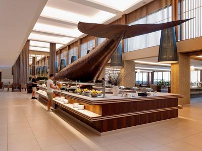Heller Hotel-Speisesaal mit Buffet und großer Skulptur in der Mitte.