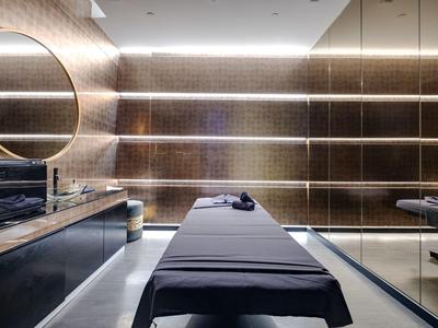 Modernes Spa-Zimmer mit zwei Massageliegen, warmen Beleuchtung und reflektierenden Wänden.