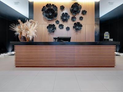 Moderner Hotel-Empfang mit hölzernem Tresen und dekorativen schwarzen Wandskulpturen.