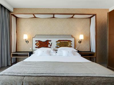 Modernes Hotelzimmer mit großem Doppelbett, dekorativen Kopfkissen und neutralen Farben.