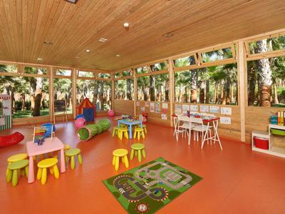 Kinderspielzimmer mit bunten Stühlen, Tischen und Spielzeug in einem holzverkleideten Raum.