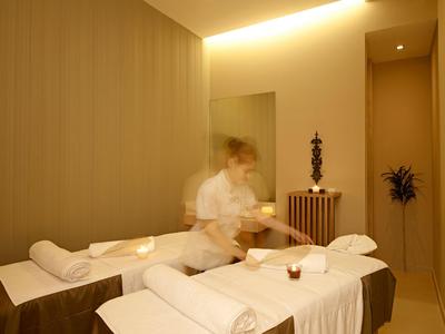 Sanfter Massageraum im Hotel mit gedimmtem Licht und zwei Behandlungsbetten.