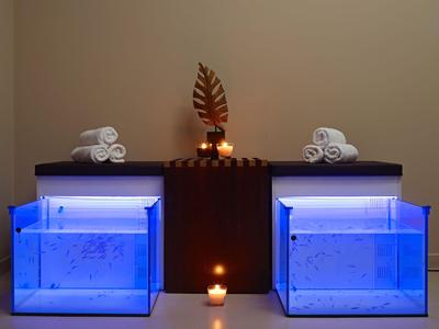 Moderner Wellnessbereich mit blau beleuchteten Wasserbecken und Teelichtern.