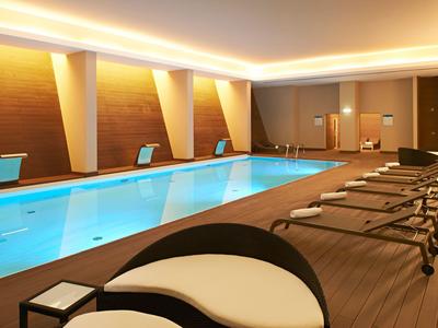 Moderner Innenpool mit Liegestühlen und indirekter Beleuchtung in einem Hotel.