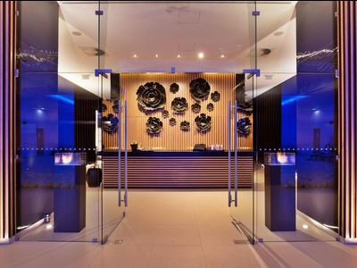 Moderne Hotellobby mit Rezeption, blauer Beleuchtung und dekorativen Wandlelementen.