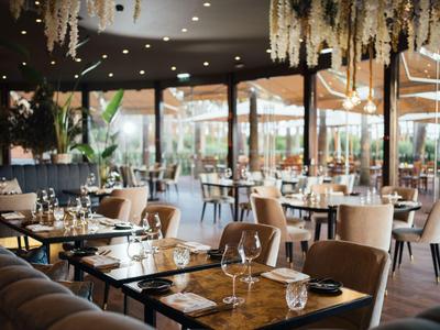 Elegantes Hotelrestaurant mit stilvollen Tischen und Stühlen sowie großer Fensterfront.