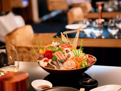 Ein eleganter Tisch mit einer Schüssel Sushi und begleitenden Saucen in einem Restaurant.