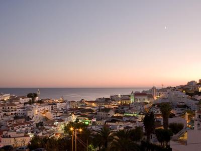 Widok na nadmorskie miasteczko o zachodzie słońca z portem i domami.