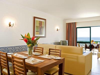 Salon z jadalnią, sofami i balkonem z widokiem na morze w pokoju hotelowym.