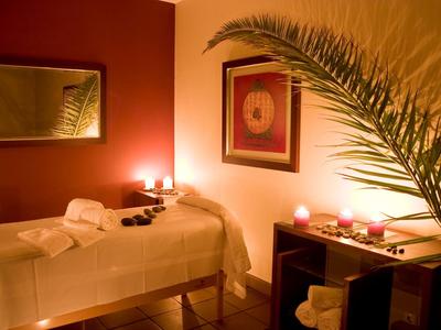 Przytulny pokój spa z łóżkiem do masażu, światłem świec i relaksującą dekoracją.