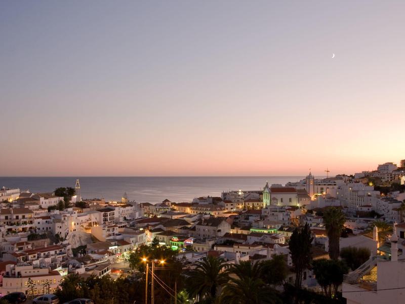 Widok na nadmorskie miasteczko o zachodzie słońca z portem i domami.