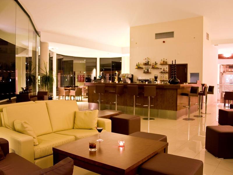 Nowoczesny hotelowy salon z wygodnymi sofami i barem przy wieczornym świetle