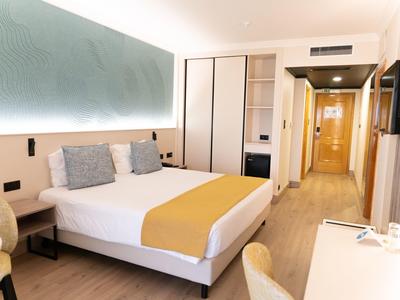 Camera d'albergo moderna con letto matrimoniale, scrivania e TV a schermo piatto.