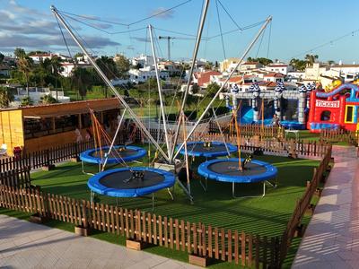 Più trampolini con una struttura a rete su prato artificiale verde, circondati da una piccola recinzione all'aperto.