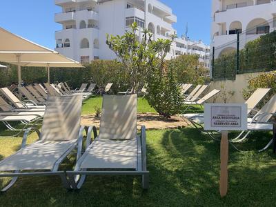 Sdraio su un prato accanto a edifici bianchi e ombrelloni sotto un cielo sereno.