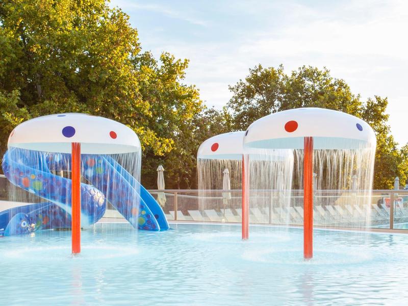 Parco acquatico con giochi d'acqua a forma di fungo e scivoli blu nella piscina per bambini