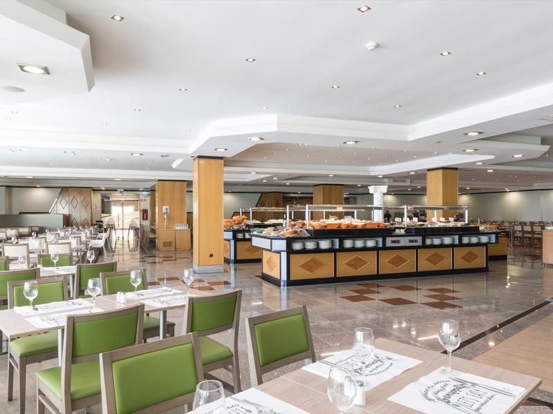 Ampia sala da pranzo con buffet e sedie verdi in un hotel.