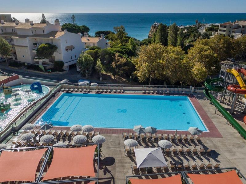 Grande piscina all'aperto con scivoli d'acqua, ombrelloni e lettini in un hotel vicino al mare.