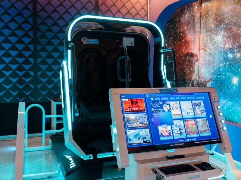 Stazione di gioco VR moderna con sedile e display di controllo in una stanza futuristica.