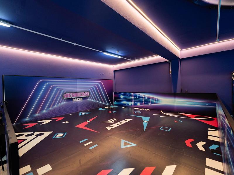 Una sala da bowling moderna con luci al neon colorate e pavimento scuro con motivi geometrici.