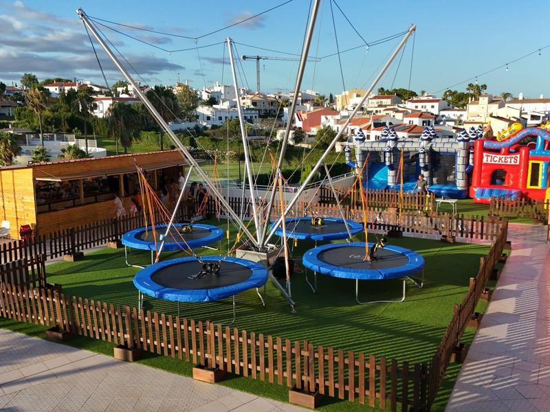 Più trampolini con una struttura a rete su prato artificiale verde, circondati da una piccola recinzione all'aperto.