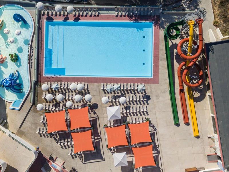 Vista aerea di un centro ricreativo con piscine, scivoli d'acqua e ombrelloni.