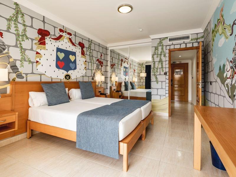 Camera d'hotel moderna con letto matrimoniale, murale colorata e mobili in legno.