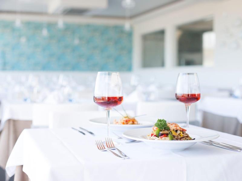 Tavolo elegante in un ristorante con tovaglia bianca, vino e cibo servito.