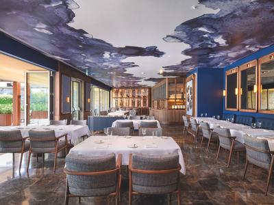Ristorante elegante con pareti blu, soffitto dipinto a cielo e arredi moderni.