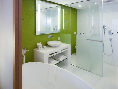 Bagno moderno con vasca autoportante, parete verde e doccia in vetro