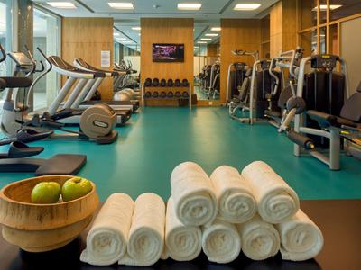 Palestra in hotel con attrezzi per esercizi, asciugamani arrotolati e frutta.