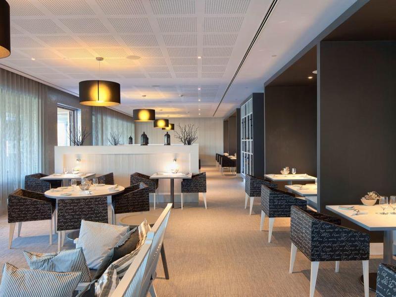 Sala da pranzo moderna di un hotel con pareti blu, grandi orologi e posti a sedere eleganti.