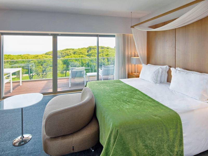 Area piscina dell'hotel con due piscine, lettini e palme con vista sul mare