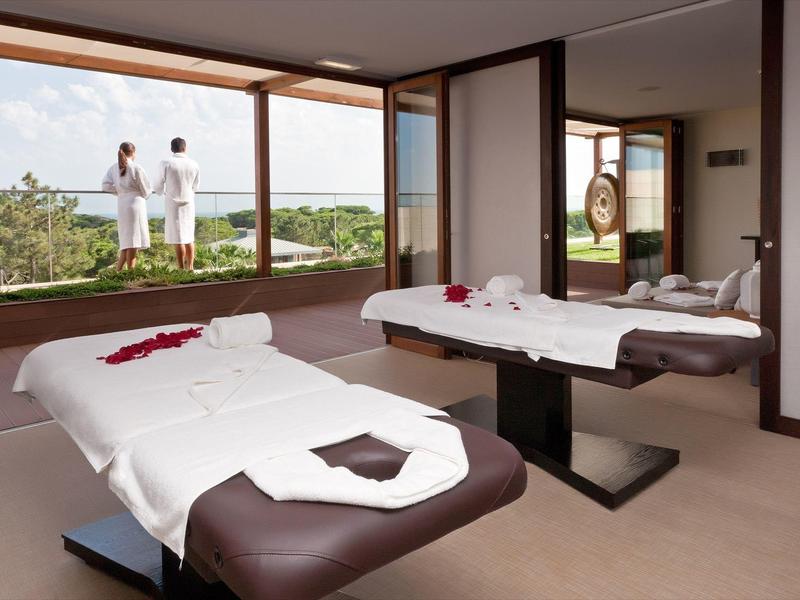 Luminosa sala spa con due lettini da massaggio e vista su paesaggio verde.