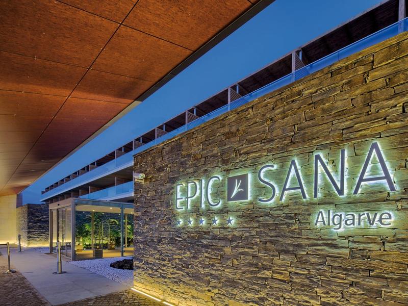 Ingresso in muro di pietra illuminato dell'hotel Epic Sana al crepuscolo