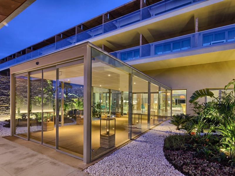 Edificio moderno con facciata in vetro e piante nell'area esterna alla luce serale