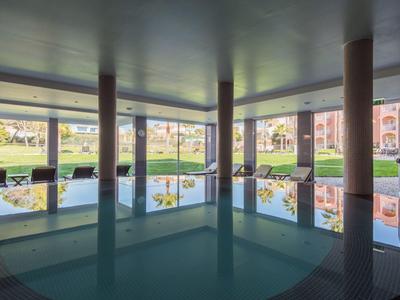 Innenpool mit großen Fenstern und Blick auf eine grüne Außenanlage bei Tageslicht