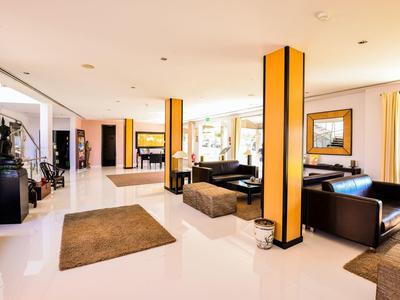 Helle Hotellobby mit gelben Säulen, schwarzen Sesseln und braunen Teppichen.