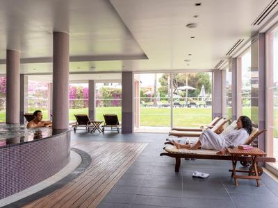 Ruhebereich mit Liegen und großen Fenstern, Blick auf eine grüne Außenanlage