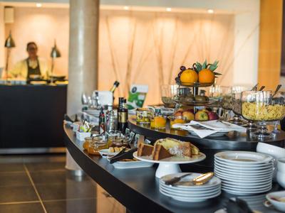 Buffet mit frischem Obst, Gebäck und Getränken in modernem Hotelrestaurant.