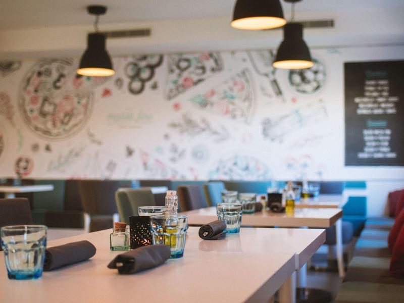 Modern eingerichteter Essbereich mit dekorativen Wandmustern und gedeckten Tischen.