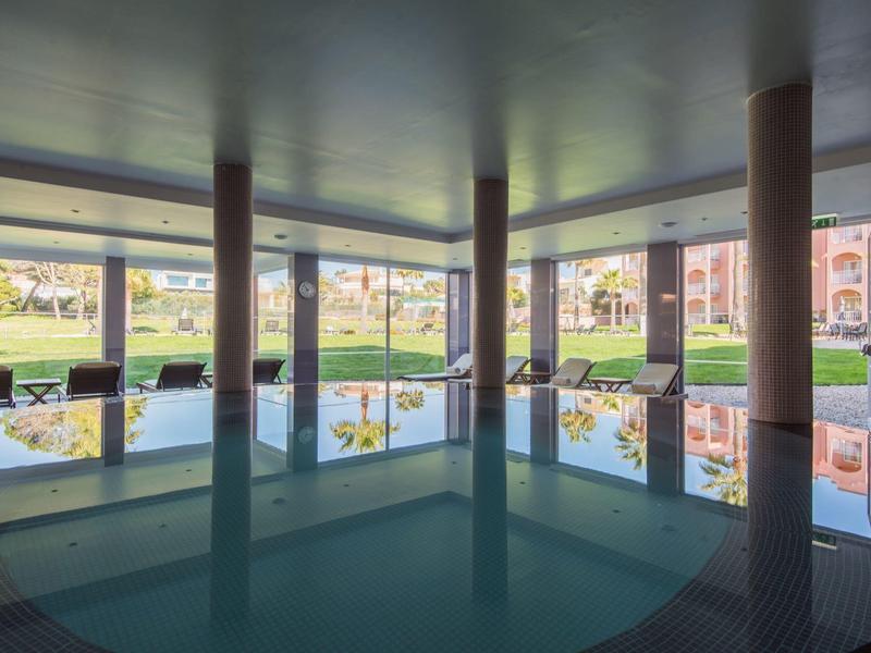 Innenpool mit großen Fenstern und Blick auf eine grüne Außenanlage bei Tageslicht