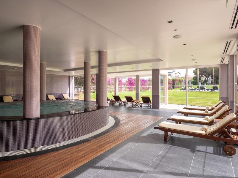 Moderner Wellnessbereich mit Rundbecken, Liegestühlen und Blick auf Gartenfläche