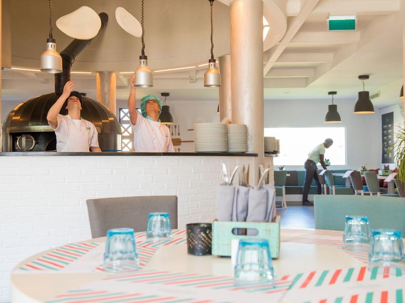 Modernes Café mit bunten Tischen, beleuchteten Lampen und Kellner bei der Arbeit.