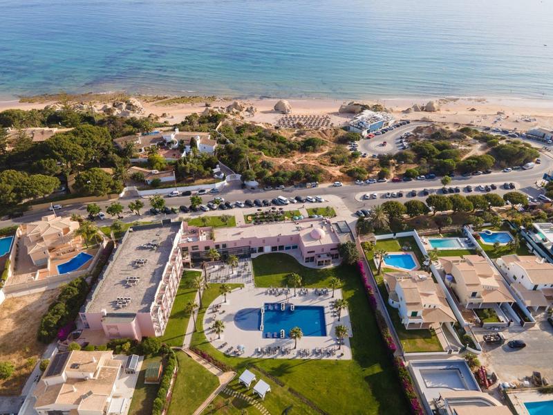 Luftaufnahme eines Strandresorts mit Pool, mehreren Gebäuden und Sandstrand am Meer