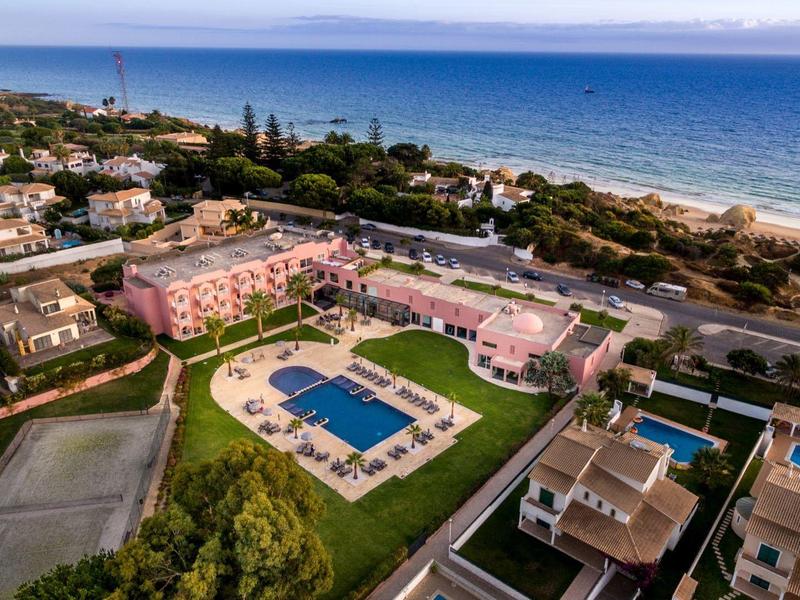 Luftaufnahme eines Resorts mit Pools, von Grünflächen umgeben und mit Blick auf das Meer.