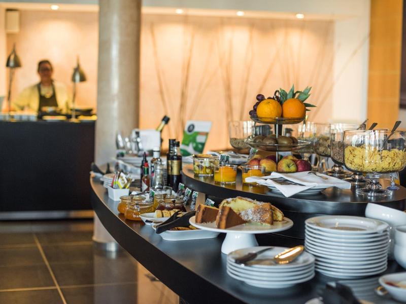 Buffet mit frischem Obst, Gebäck und Getränken in modernem Hotelrestaurant.