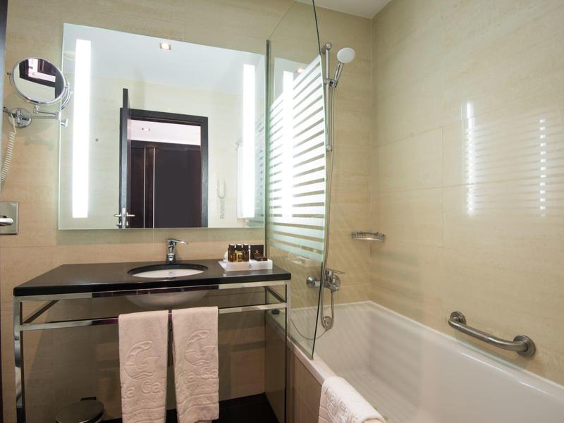 Modernes Badezimmer mit beleuchtetem Spiegel, Waschbecken, Handtüchern und Badewanne.