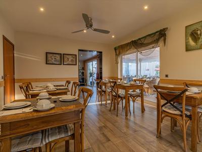 Gemütlicher Speiseraum mit Holztischen und Stühlen, gedeckt für mehrere Gäste.