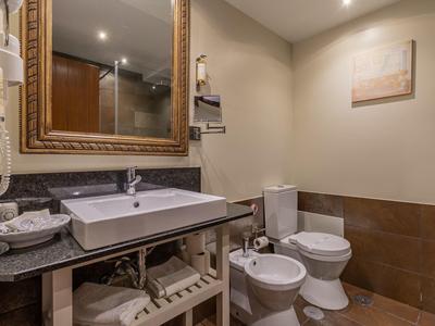 Modernes Badezimmer mit Waschbecken, Toilette, Bidet und großem Spiegel in neutralen Tönen.